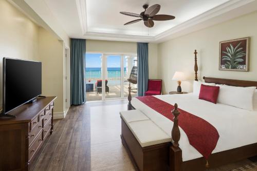 a bedroom with a bed and a television and the ocean at Jewel Grande Montego Bay Resort and Spa in Montego Bay