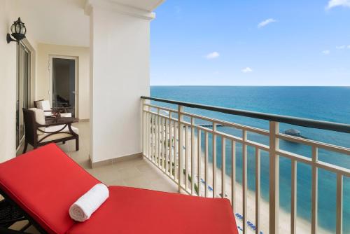 a balcony with a red bench and the ocean at Jewel Grande Montego Bay Resort and Spa in Montego Bay