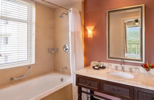 a bathroom with a tub and a sink and a mirror at Jewel Grande Montego Bay Resort and Spa in Montego Bay