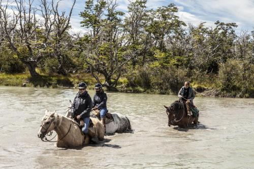a group of people riding horses through a river at Pampa Lodge, Quincho & Caballos in Torres del Paine