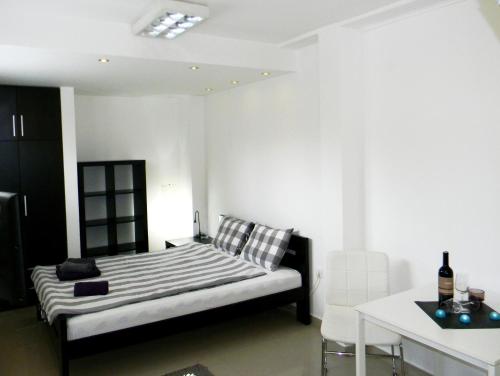 a white bedroom with a bed and a table at Apartments Luka in Kragujevac