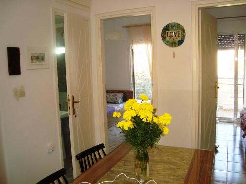 a dining room table with a vase of yellow flowers at Apartment for Family 2 in Kallithea Halkidikis