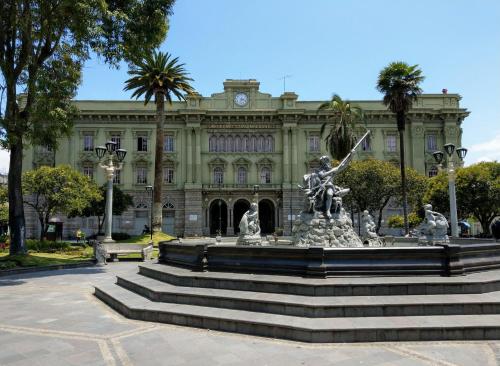 a fountain in front of a building with a statue at Hotel Rincon Aleman in Riobamba