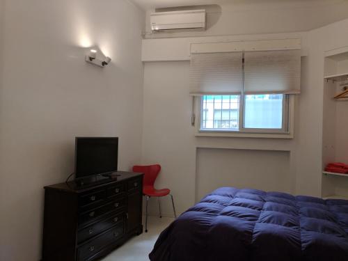 1 dormitorio con 1 cama, TV y silla roja en La mejor ubicación en Buenos Aires