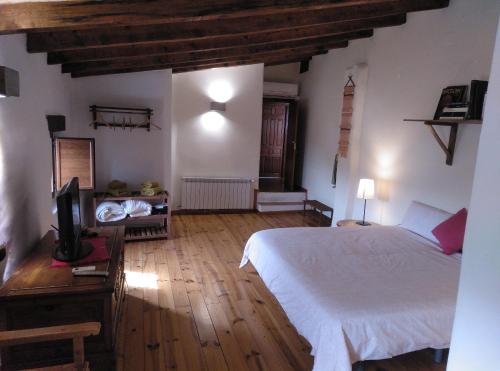 a bedroom with a white bed and a television at Casas Rurales Planeta Chicote in Zafra de Záncara