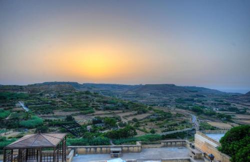 a view from the top of a building with the sunset in the background at Cornucopia Hotel in Xagħra