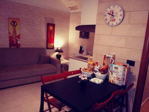 a kitchen with a black table with chairs and a clock at Filioli Apartment in Bari