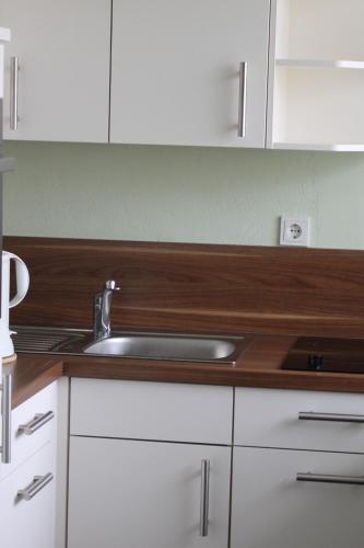 a kitchen with a sink and white cabinets at Fewo Geesteblick - Dietmar Strauch in Bremerhaven