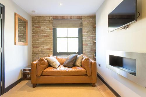 a brown leather couch in a living room with a television at Forbee Studios in London