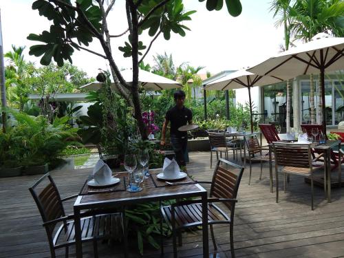a man standing on a deck with tables and chairs at MEN's Resort & Spa (Gay Hotel) in Siem Reap