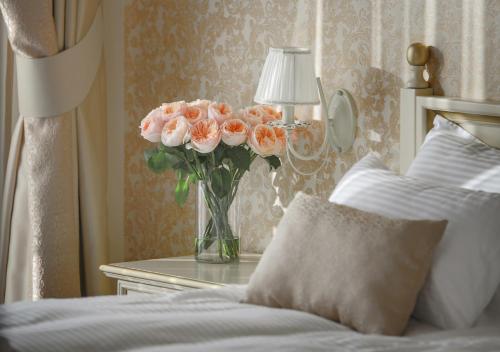 a vase of pink roses on a table next to a bed at FENIX TOWN in Vinnytsya