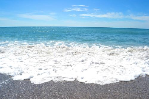 a beach with white foam on the sand and the ocean at Casa Caracol in Playa Coronado