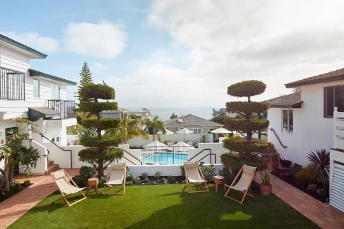 a patio with chairs and a yard with a pool at Hotel Joaquin in Laguna Beach