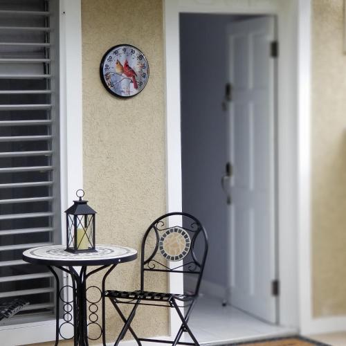 a table and chair next to a clock on a porch at Millsborough B&B in Billy Dun