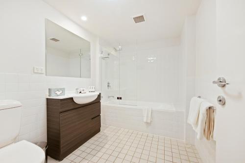 ein weißes Badezimmer mit einer Badewanne und einem Waschbecken in der Unterkunft Quest Newcastle in Newcastle