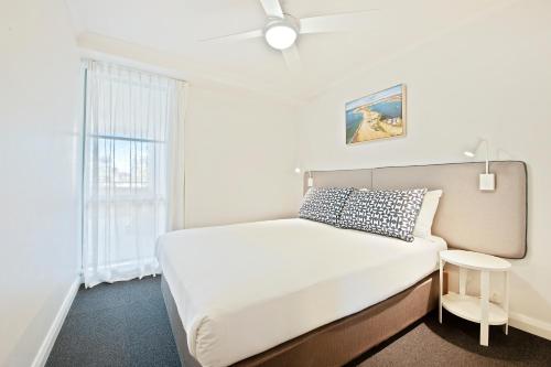 a white bedroom with a bed and a window at Quest Newcastle in Newcastle