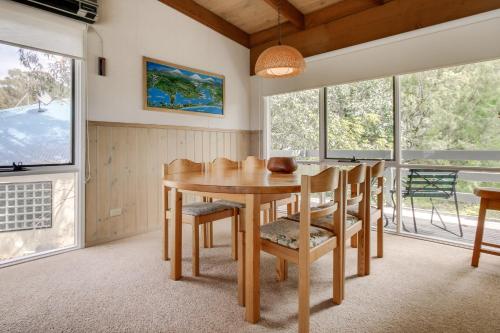 a dining room with a table and chairs and windows at Millimgimbi in Metung