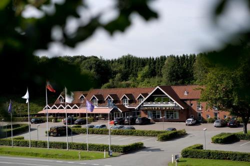 a hotel with cars parked in a parking lot at Nilles Kro in Sabro