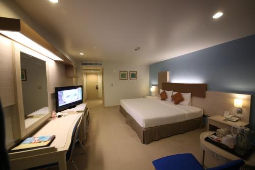 a hotel room with a bed and a television at Sunshine Vista Hotel in Pattaya Central