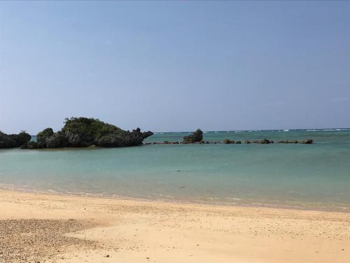 a sandy beach with trees in the water at ペンション ラナカイハウス沖縄 in Onna