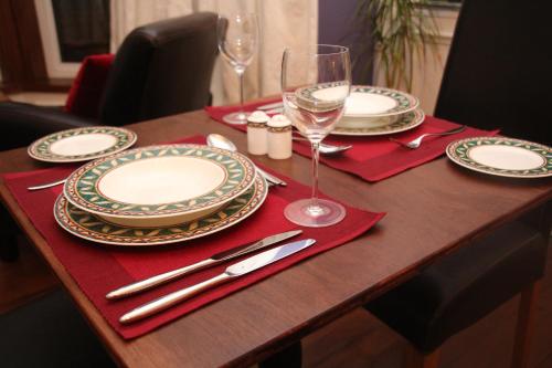 een houten tafel met borden en wijnglazen erop bij No 9 The Guest House Perth in Perth