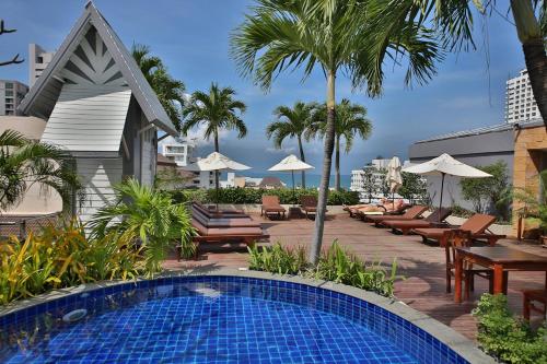 a swimming pool with chairs and umbrellas at a resort at Sunshine Vista Hotel in Pattaya Central