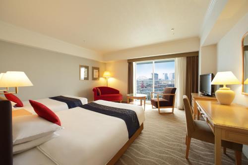 a hotel room with two beds and a desk at Kobe Meriken Park Oriental Hotel in Kobe