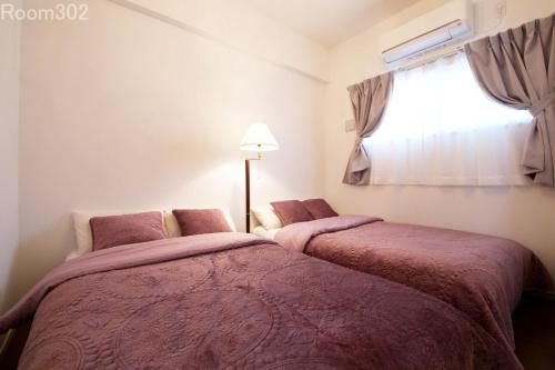 two beds in a room with a window at La Fonte UK2 in Ginowan