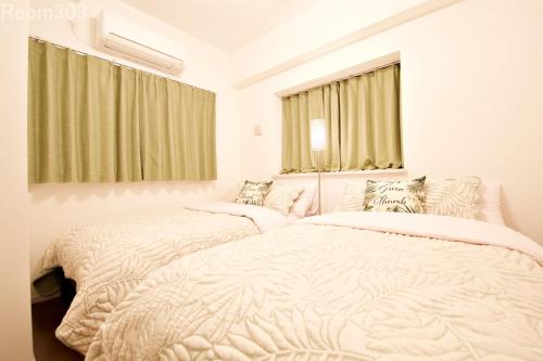 two twin beds in a bedroom with a window at La Fonte UK2 in Ginowan