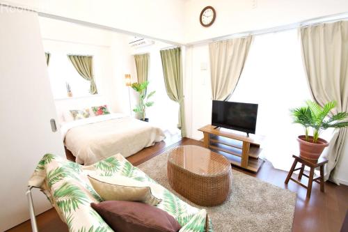 uma sala de estar com uma cama e um sofá em La Fonte UK2 em Ginowan