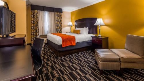 Best Western Plus Barsana Hotel & Suites في مدينة اوكلاهوما: غرفه فندقيه بسرير واريكه