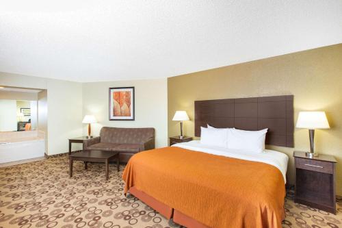 a hotel room with a bed and a chair at AmericInn by Wyndham Cedar Falls in Cedar Falls