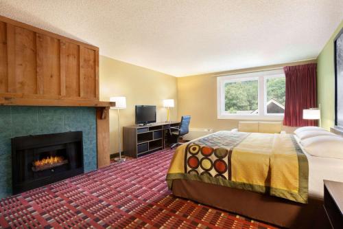 a hotel room with a bed and a fireplace at Super 8 by Wyndham Cherokee in Cherokee