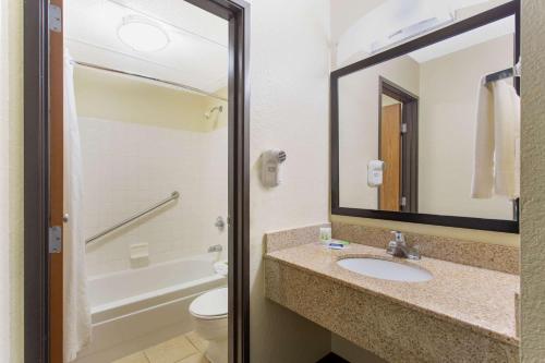 a bathroom with a sink and a toilet and a mirror at AmericInn by Wyndham Burlington in Burlington