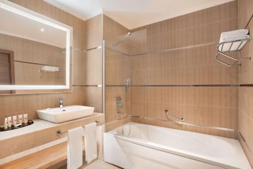 uma casa de banho com uma banheira, um lavatório e um espelho. em Ramada Plaza Rize em Rize