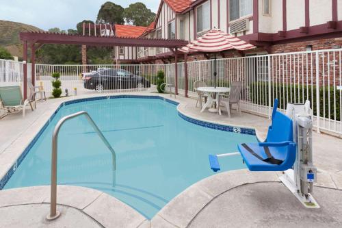 a swimming pool with a chair and a table at Super 8 by Wyndham Santa Clarita/Valencia in Santa Clarita