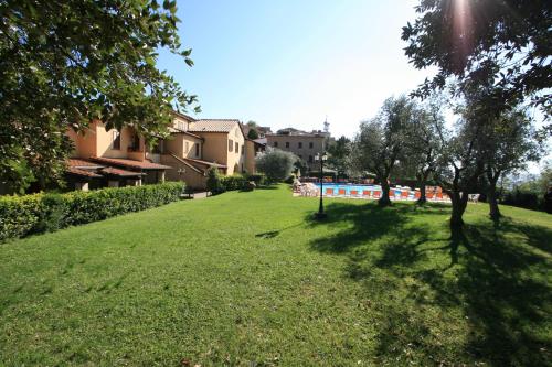 a green yard with trees and buildings in the background at Villa Nencini in Volterra