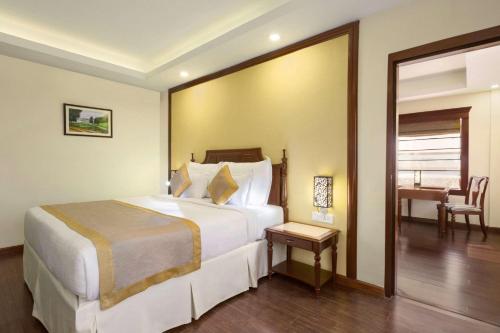 a hotel room with a large bed and a table at Ramada Jamshedpur Bistupur in Jamshedpur