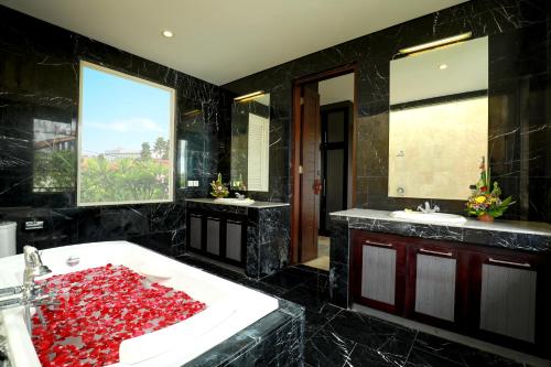 La salle de bains est pourvue de 2 lavabos et d'une grande baignoire blanche avec des roches rouges. dans l'établissement Villa The Hotman Paris V Canggu, à Canggu