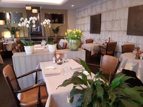 a restaurant with white tables and chairs and flowers at De Eenhoorn in Oostburg