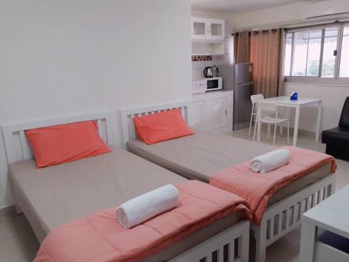 a bedroom with two beds and a kitchen with a table at New Room in Nonthaburi