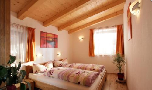 Schlafzimmer mit einem Bett und einem Fenster mit orangefarbenen Vorhängen in der Unterkunft Appartement Annemarie in Brixen im Thale