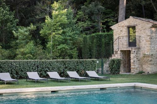 a group of lounge chairs next to a swimming pool at Domaine de Fontenille in Lauris