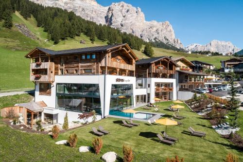 a house in the mountains with a yard with chairs at Hotel Störes - Living Nature Hotel in San Cassiano