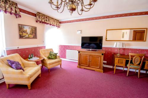 a living room with a flat screen tv and furniture at Hotel Garden in Bolesławiec