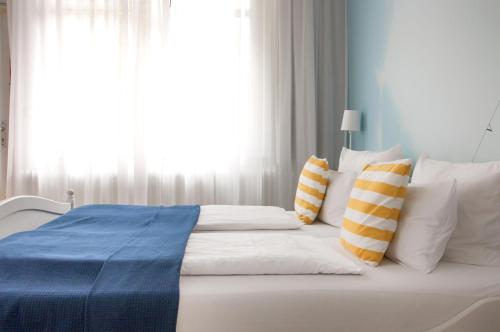 a bedroom with a white bed with pillows and a window at Lieblingsplatz Strandhotel in Sankt Peter-Ording