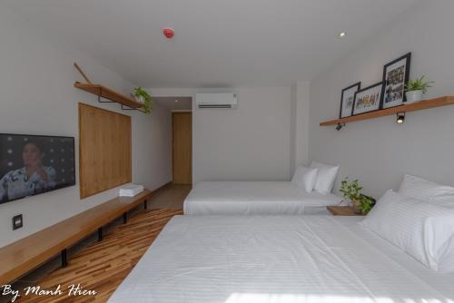 a hotel room with two beds and a tv at Mojzo Inn Boutique Hotel in Nha Trang