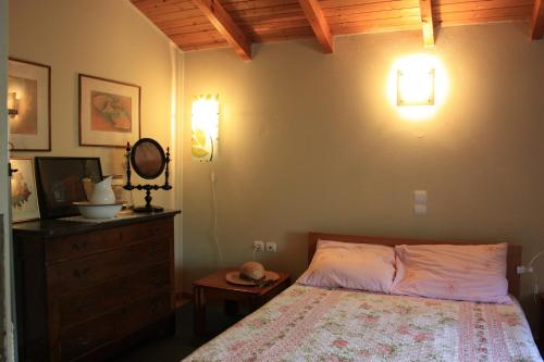 a bedroom with a bed and a dresser and lights at Mercouri stone cottage in Korakokhórion
