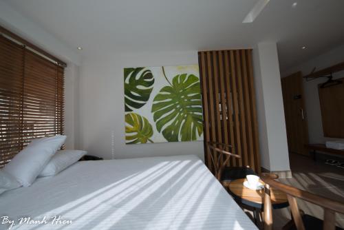 a bedroom with a bed and a table and a painting at Mojzo Inn Boutique Hotel in Nha Trang