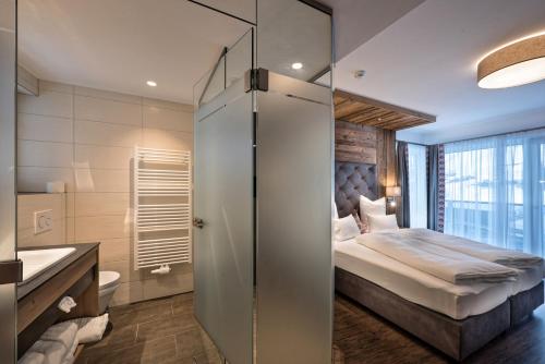 a room with a bed, a refrigerator, and a window at Hotel Eldorado in Ischgl